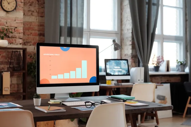 A stylish office setup featuring a computer displaying a graph on advertising trends. Programmatic experimentation